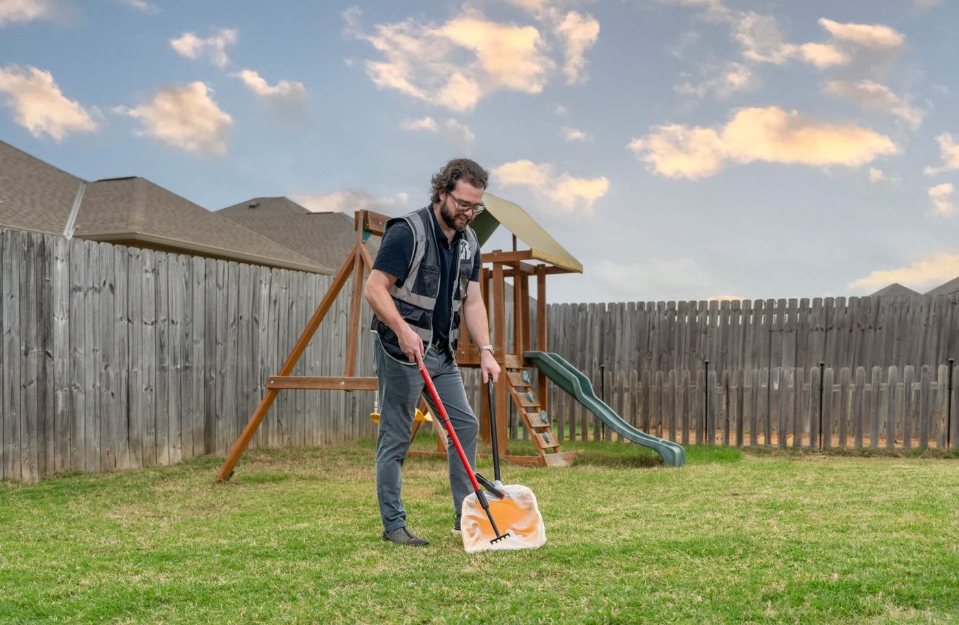  Man scooping poop in a backyard 
